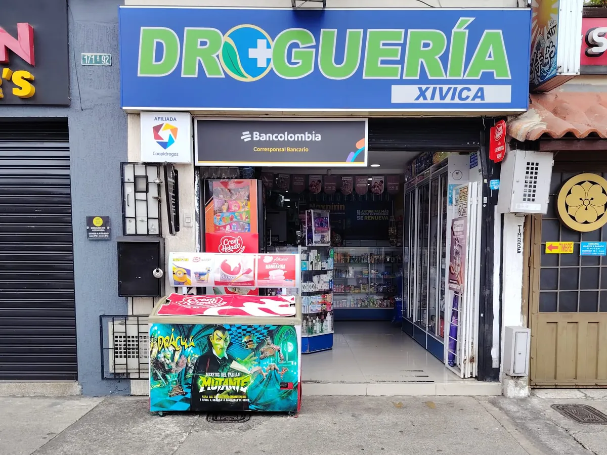 Fachada de la sede Villa del Prado: aviso azul con la palabra Droguería en verde sobre la puerta de entrada